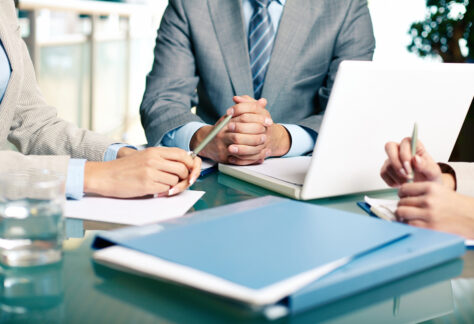 Close-up of hands of boss at workplace with laptop and hands of two females near by